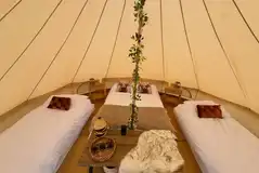 Bell tent interior furnished with a double and two single beds
