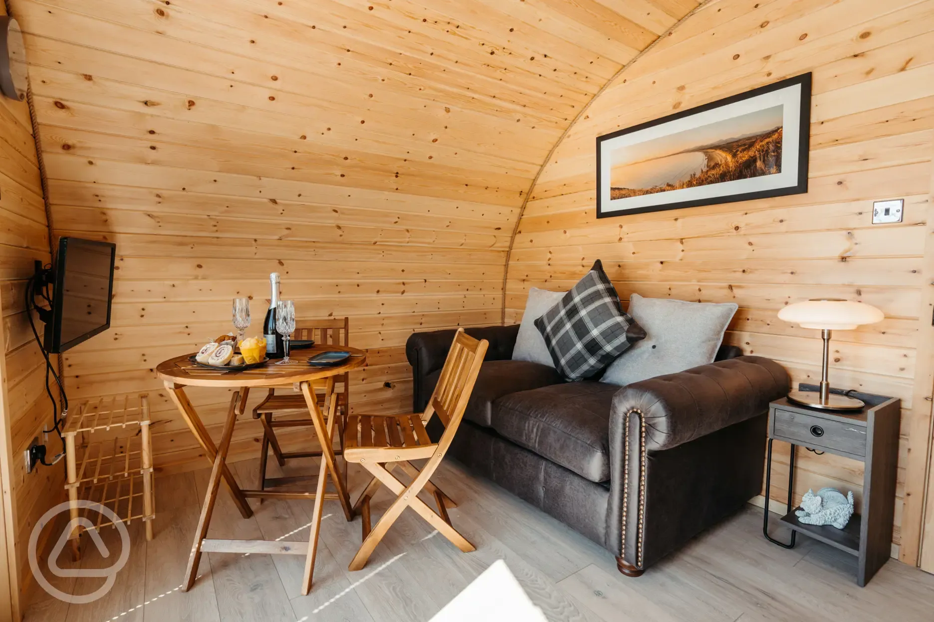 Luxury ensuite glamping pod living area with sofa, dining table and TV Luxury ensuite glamping pod living area with sofa, dining table and TV