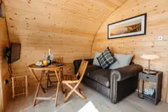 Luxury ensuite glamping pod living area with sofa, dining table and TV