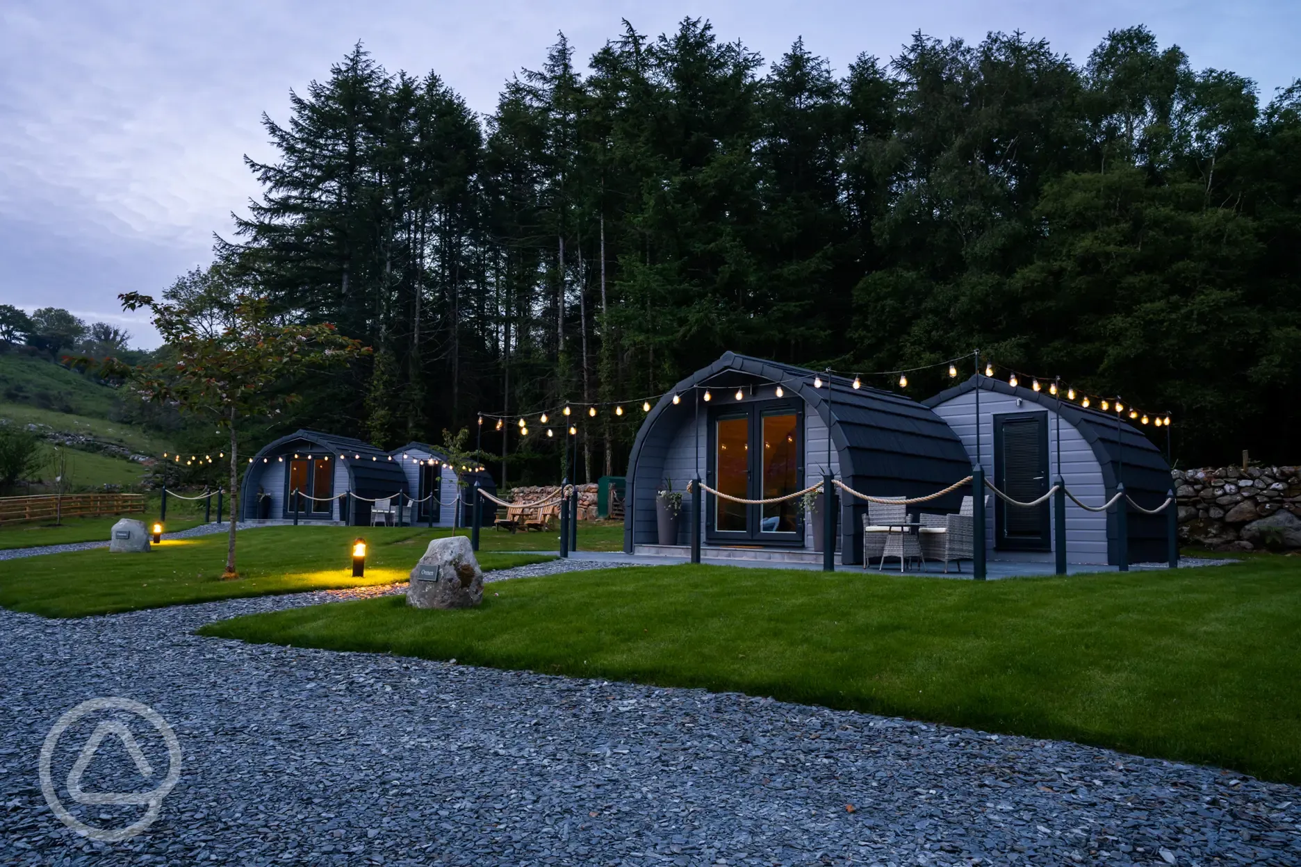Luxury ensuite glamping pods at night with outdoor festoon lighting Luxury ensuite glamping pods at night with outdoor festoon lighting