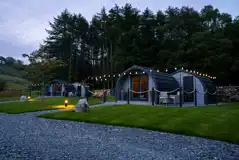 Luxury ensuite glamping pods at night with outdoor festoon lighting