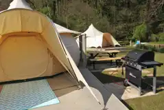 Unfurnished bell tent with an outdoor BBQ and picnic bench