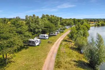 Optional electric grass pitches beside the fishing lake at Gatton Waters