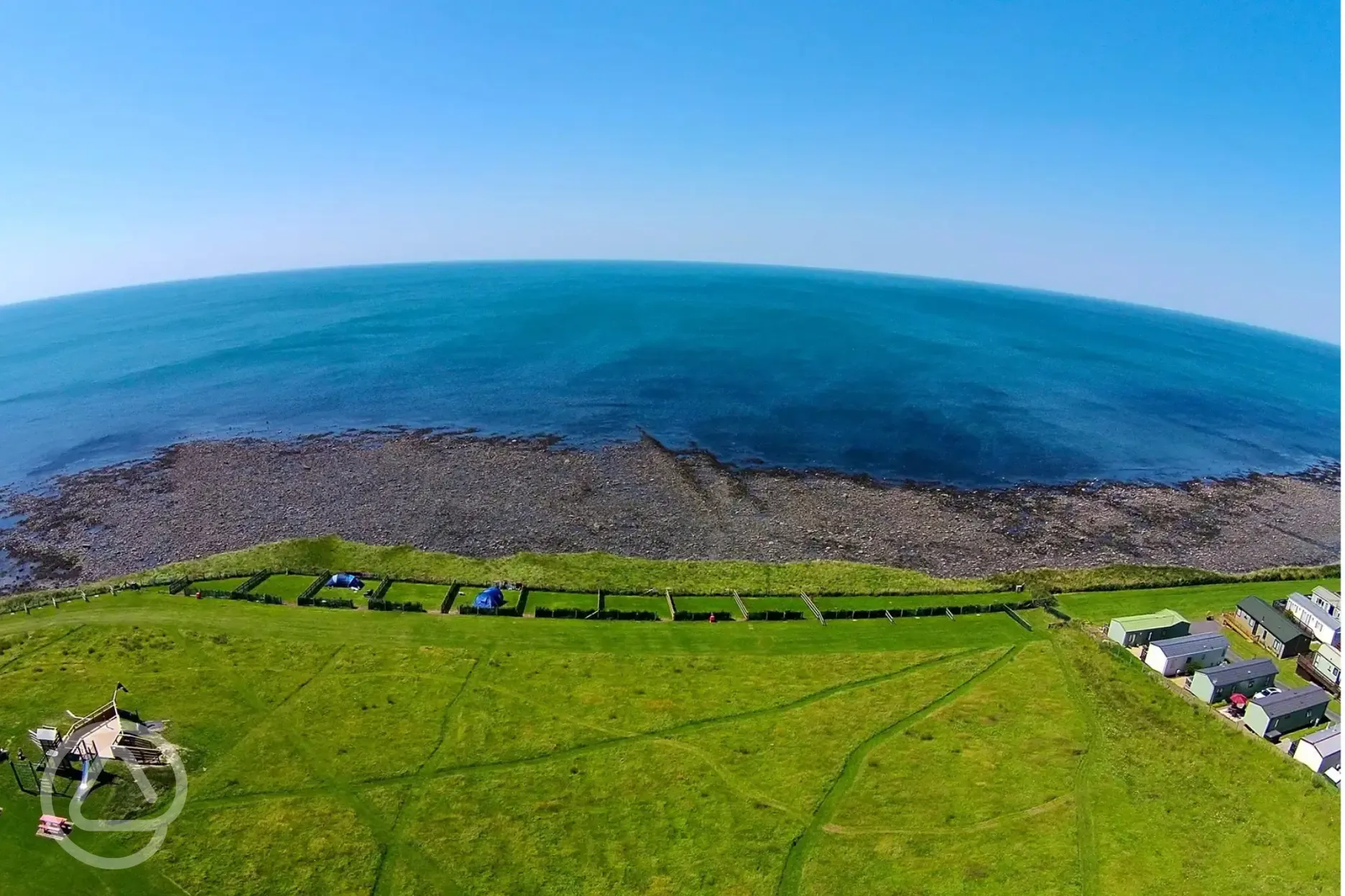 Aerial of grass pitches with distant views of Cardigan Bay Beach