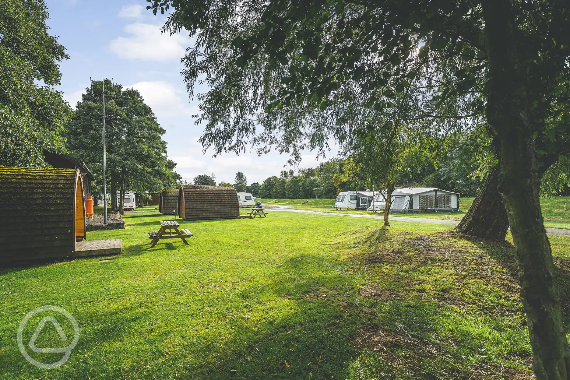 Electric hardstanding touring pitches and camping pods, surrounded by trees