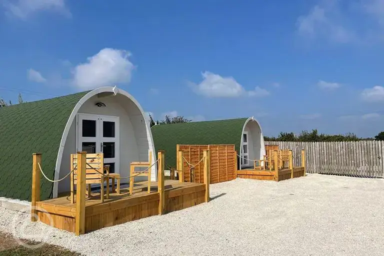 Glamping pods with a small wooden deck and seating area