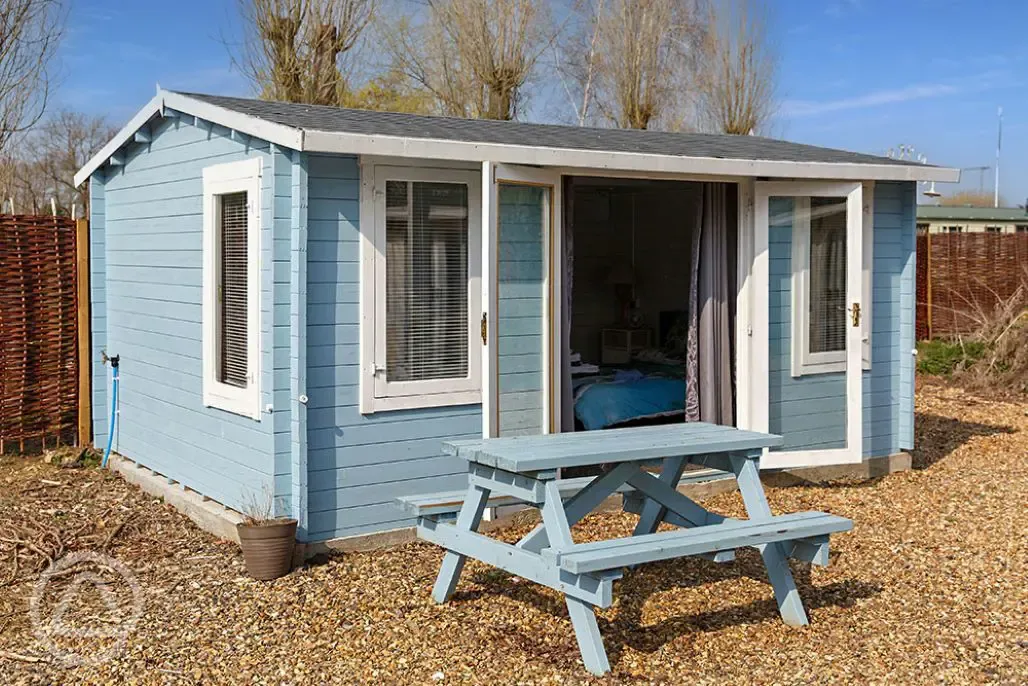 Beach hut cabin with a picnic bench at Diglea Holiday Park