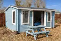 Beach hut cabin with a picnic bench at Diglea Holiday Park