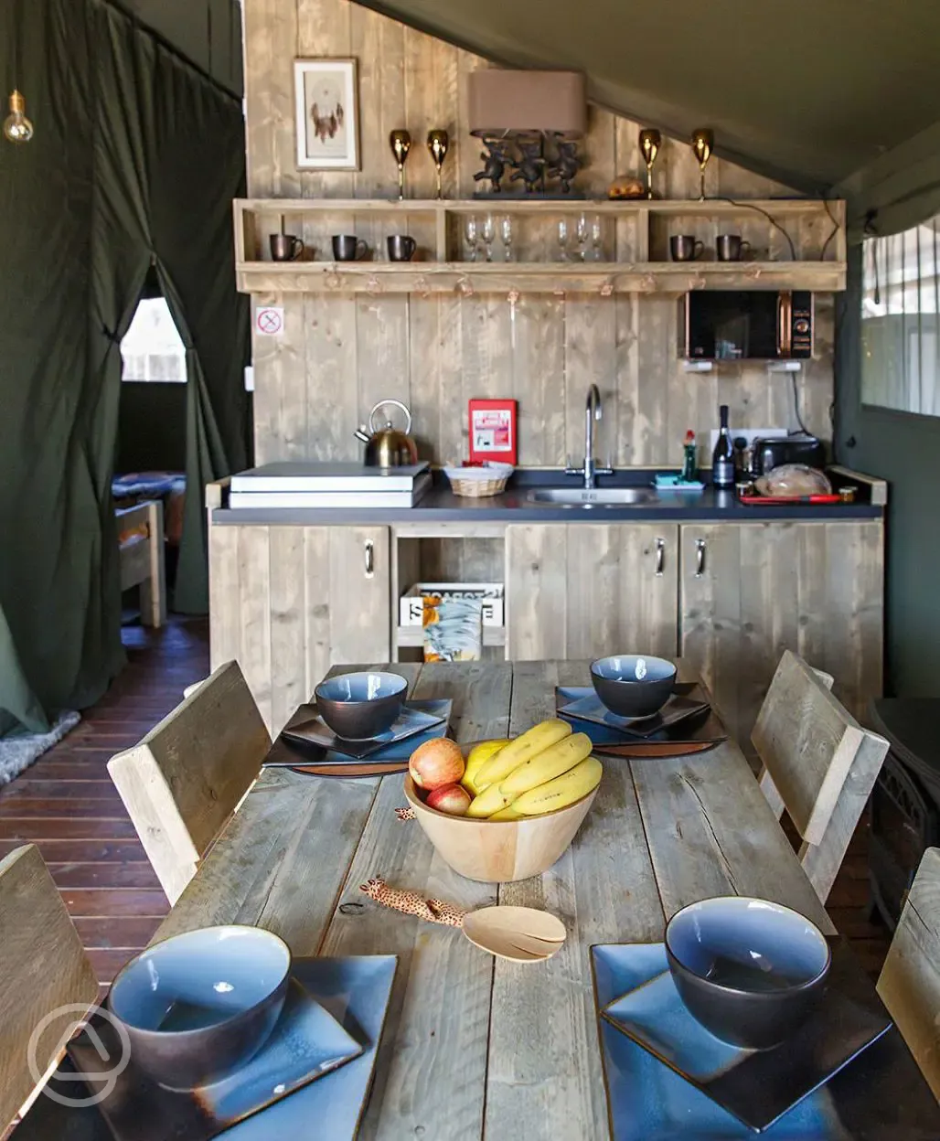 Safari tent kitchen with crockery, cutlery, and utensils