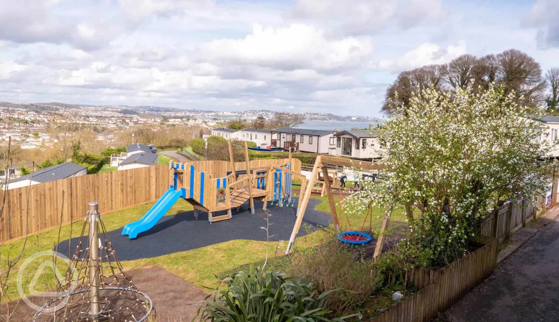 Children's play area with swings, climbing frames and lodges in the distance