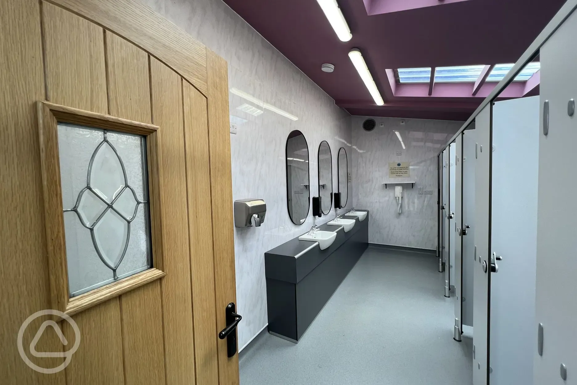 Women's bathroom with cublicles, sinks, mirrors and hand dryer