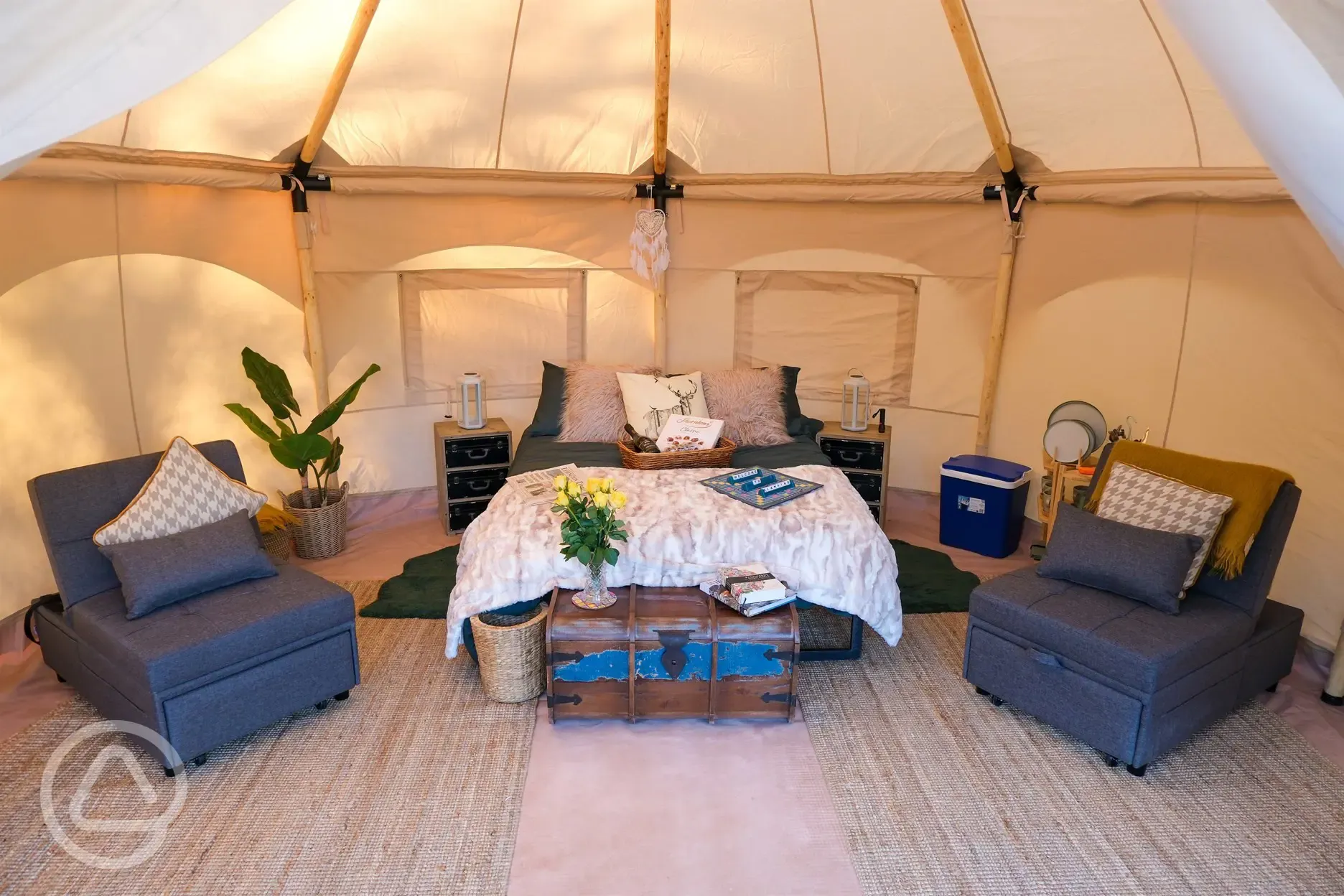 Furnished glamping bell tent with a double bed and chairs
