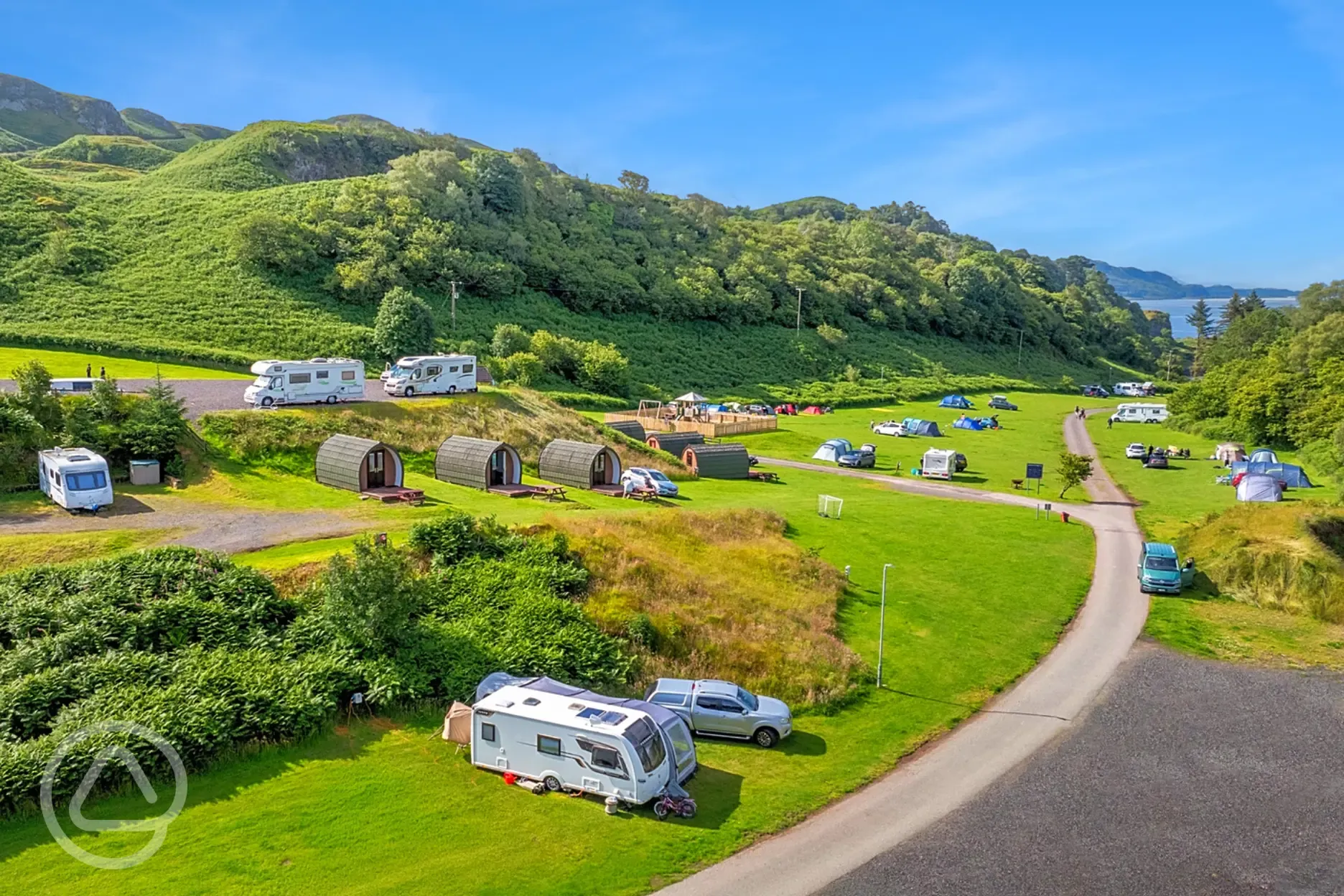 Aerial of Oban Holiday Park, surrounded by hills and with views towards the sea