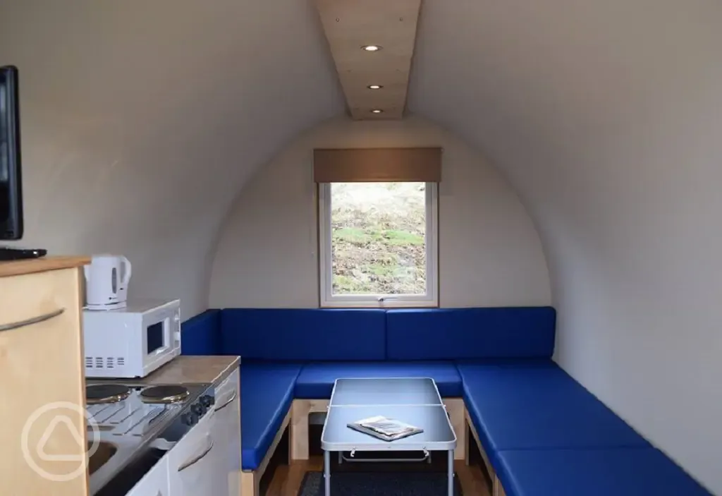 Camping pod interior with mattresses, folding table, lighting and heating