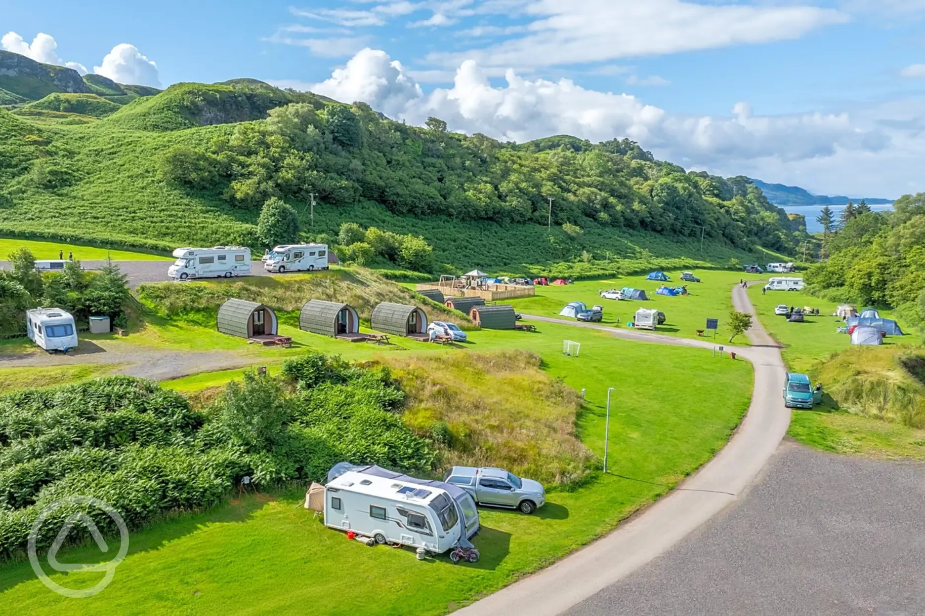 Aerial of Oban Holiday Park, surrounded by hills and with views towards the sea
