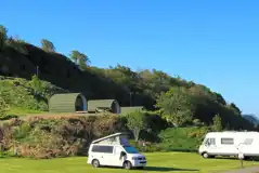 Electric grass pitches with 16 amp electric hook ups with camping pods behind Electric grass pitches with 16 amp electric hook ups with camping pods behind