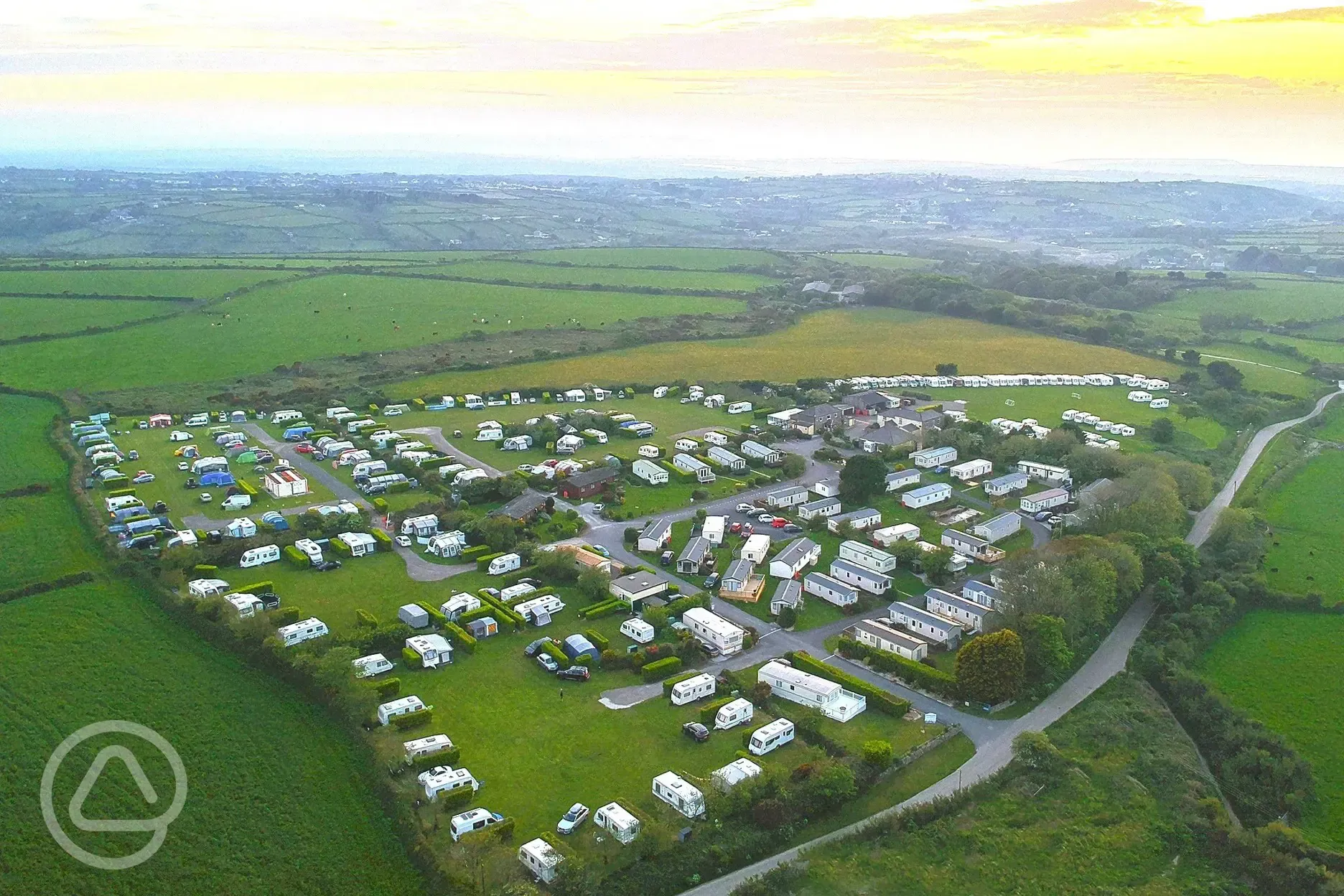 Aerial shot of Lanyon Holiday Park at sunset, surrounded by fields