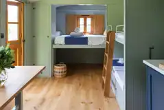 Shepherd's hut interior with a double bed and fold down bunk beds