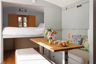 Shepherd's hut interior with a double bed and fold down bunk beds