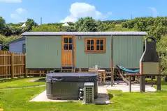 Shepherd's hut with a hot tub and garden area at Sun Haven Holiday Park