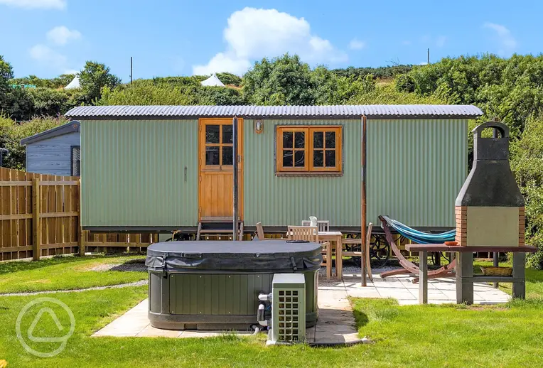 Shepherd's hut with a hot tub and garden area at Sun Haven Holiday Park