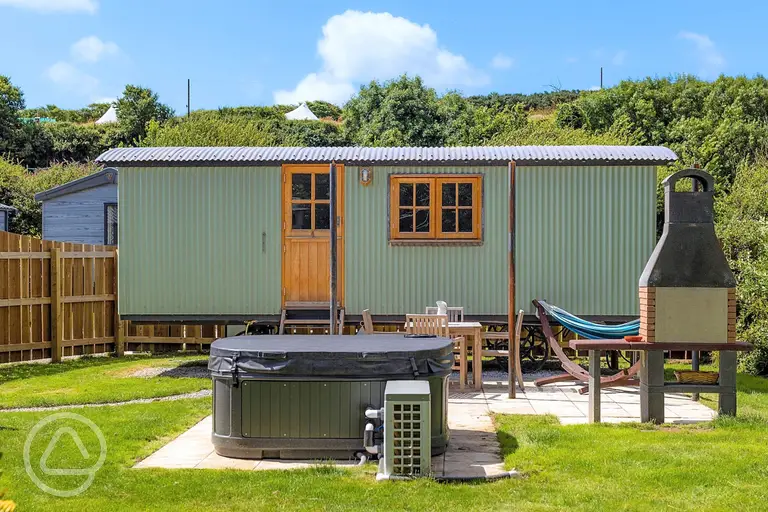 Shepherd's hut with a hot tub and garden area at Sun Haven Holiday Park