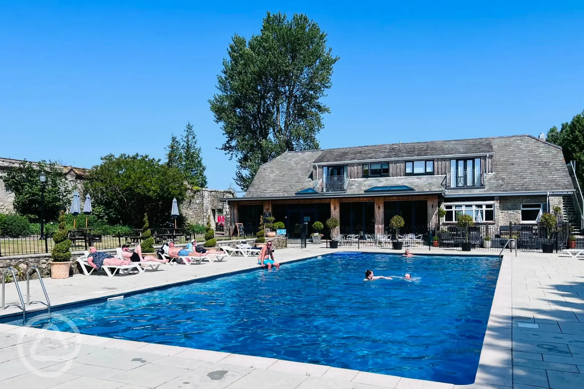 Overview of heated outdoor swimming pool with sun loungers and the Core cafe Overview of heated outdoor swimming pool with sun loungers and the Core cafe