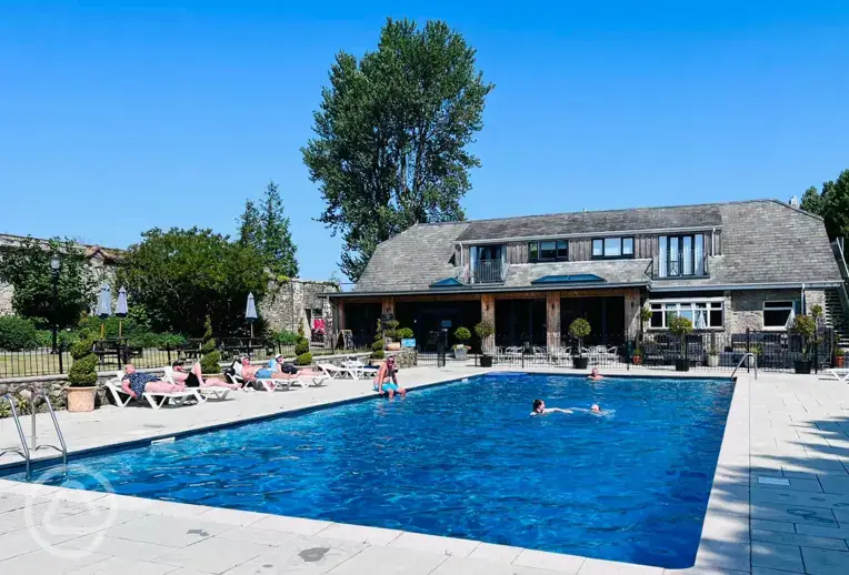 Overview of heated outdoor swimming pool with sun loungers and the Core cafe