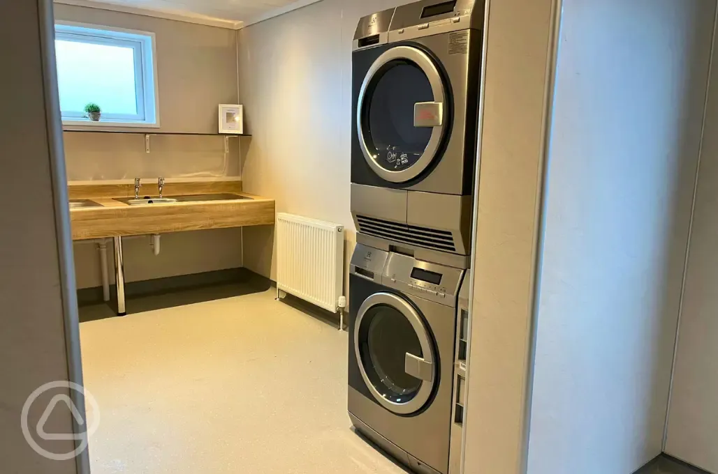 Laundry room with coin operated washers and dryers, ironing facilities and sinks