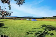 Non electric grass pitches with distant mountain views at Balloch O Dee