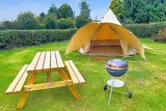 Unfurnished bell tent includes a picnic table and charcoal BBQ
