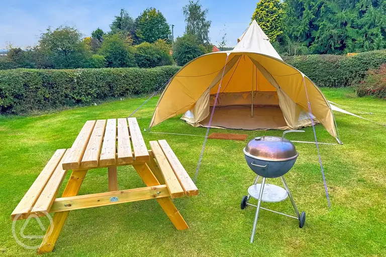 Unfurnished bell tent includes a picnic table and charcoal BBQ