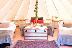 Bell tent interior with a double bed and two single camp beds