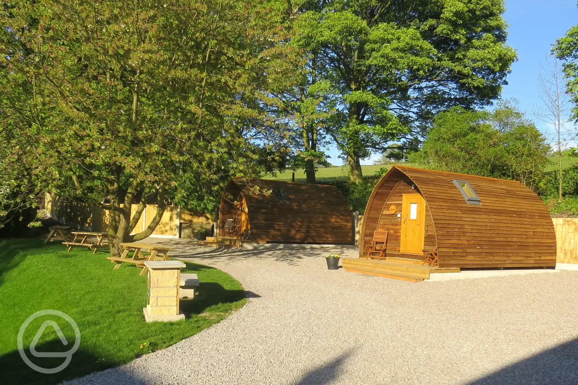 Camping pods with surrounding trees and picnic benches