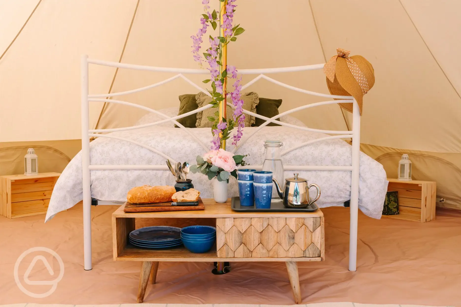 Bell tent interior with a double bed and camp beds for kids