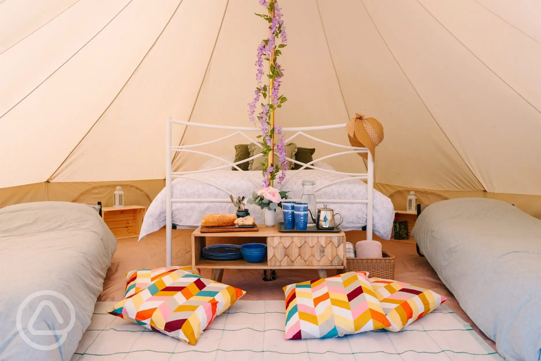 Bell tent interior with a double bed and camp beds for kids