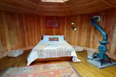 Wooden cabin interior with a double bed and log burner