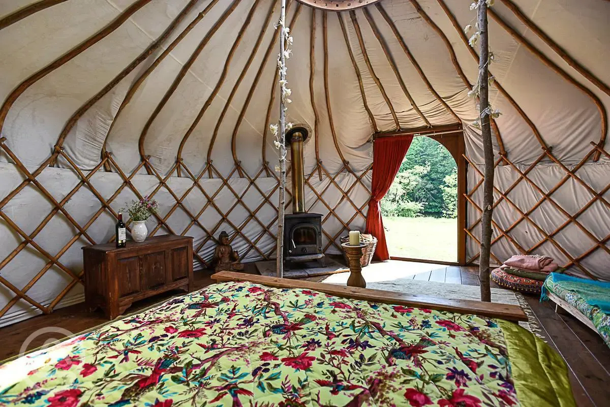 Croglin yurt interior with a double bed, futon and log burner