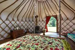 Croglin yurt interior with a double bed, futon and log burner
