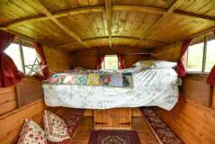 Gypsy caravan interior with a raised double bed and seating below