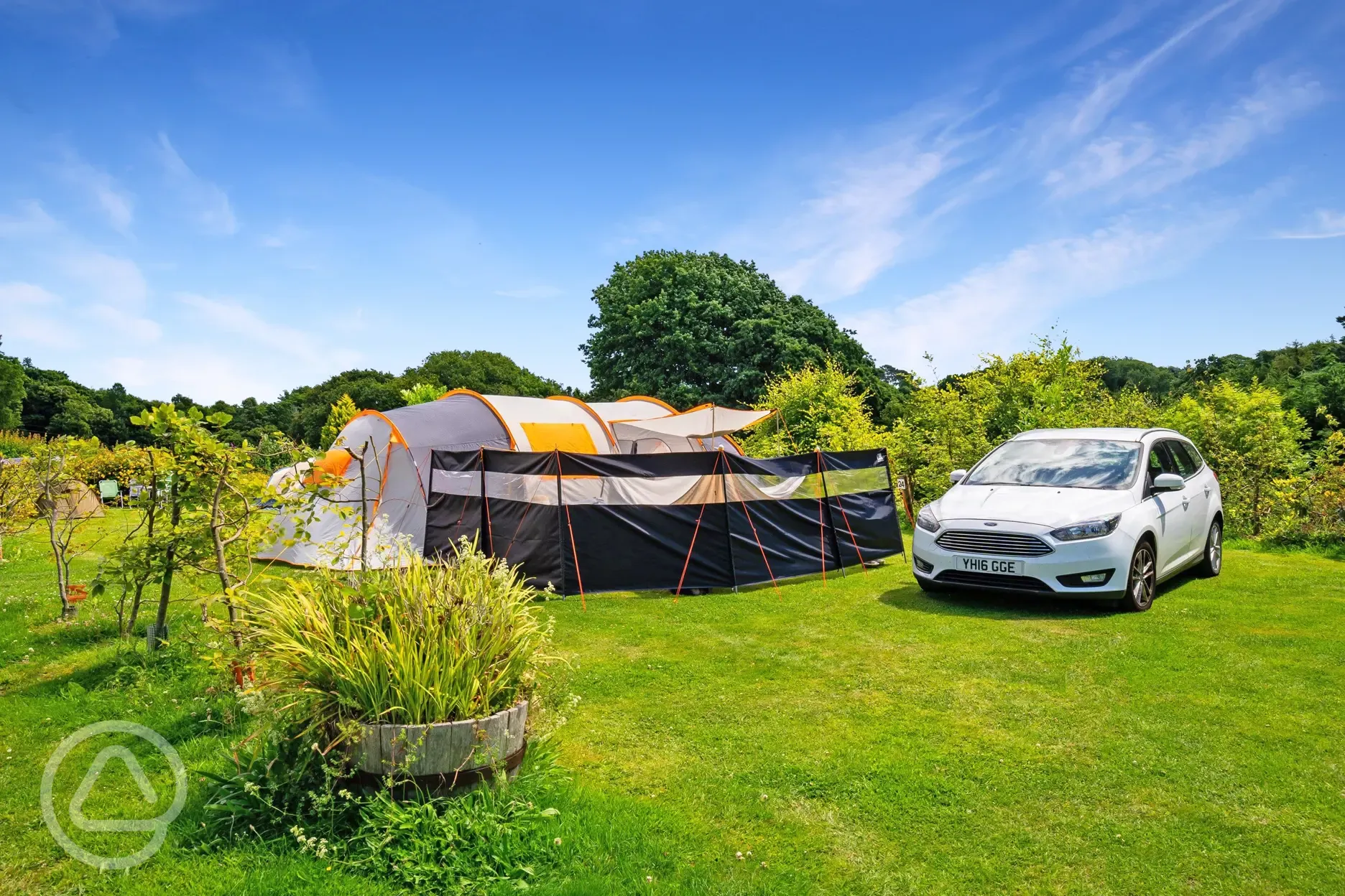 Large tent on a grass pitch with surrounding planting