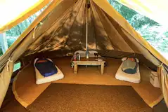 Wild glamping bell tent with beds, a table, and cooking equipment