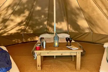 Bell tents furnished with beds, a table and cooking equipment