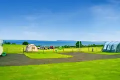 Large tents on electric grass pitches with views towards the coast Large tents on electric grass pitches with views towards the coast
