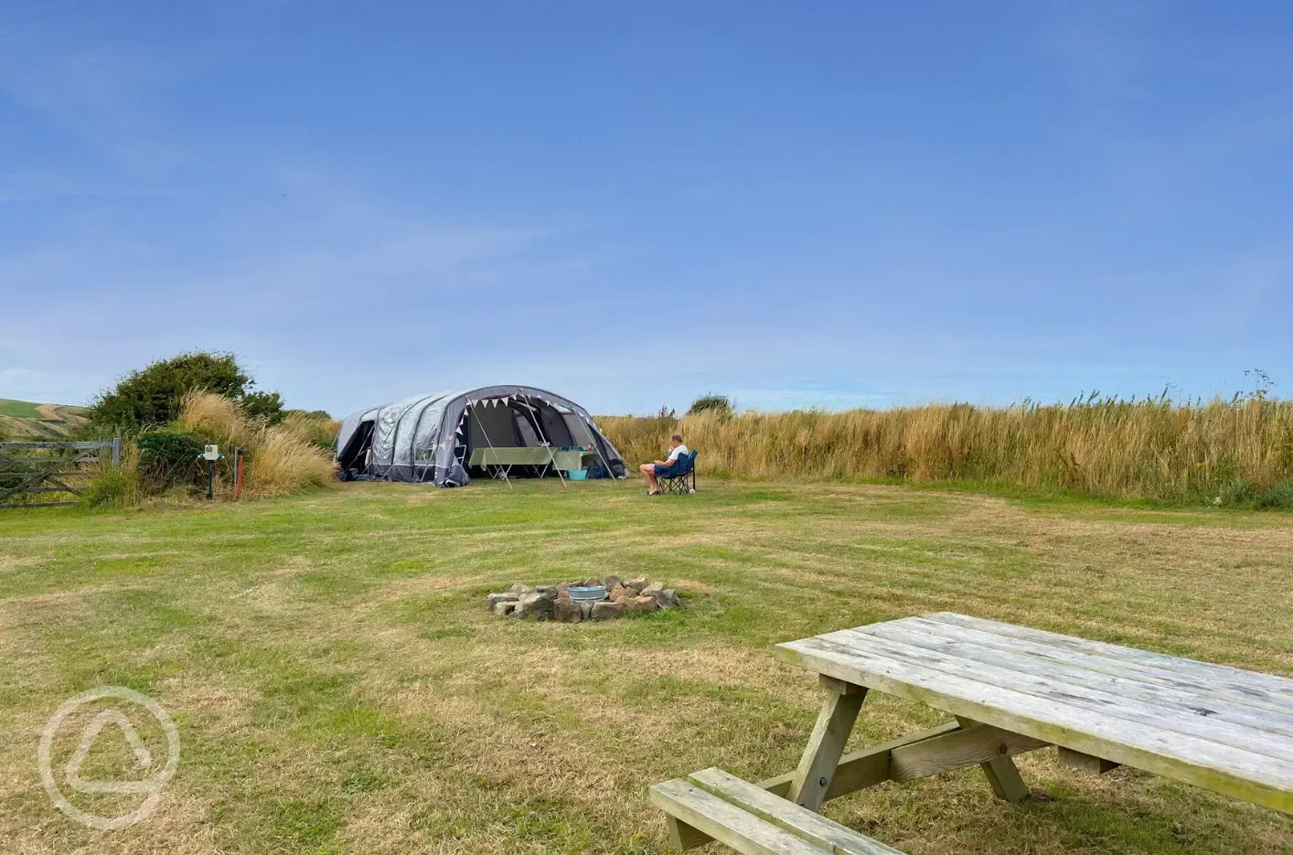 Large tent on grass pitches with optional electric, picnic benches and fire pits