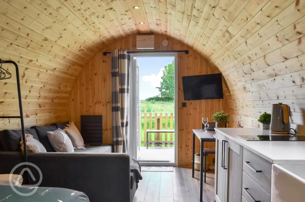 Glamping pod interior with a sofa bed, TV and small table and chairs