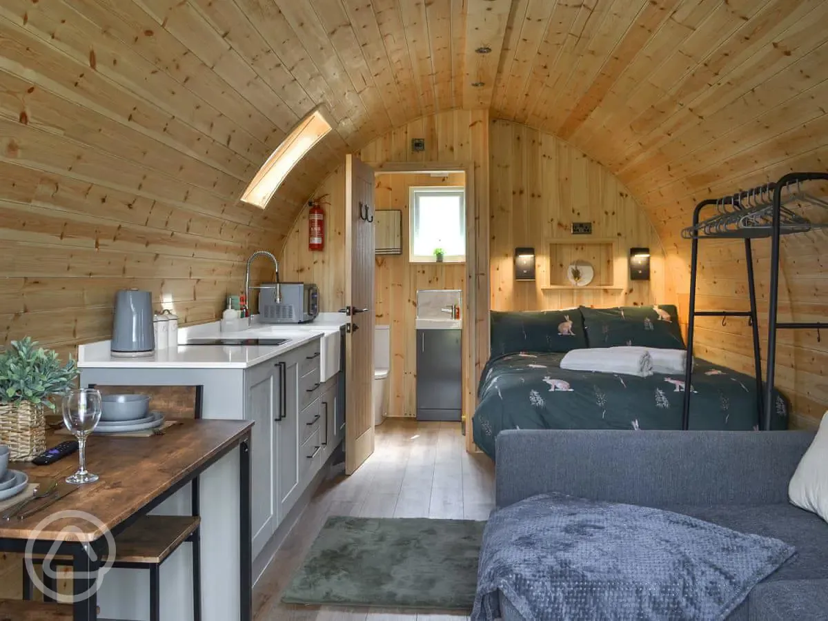 Glamping pod interior with a double bed, double sofa bed and kitchenette