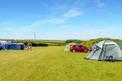 Grass pitches at Heritage Coast Campsite with space for a parked car