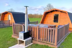 Standard glamping pods with hot tubs with decking area, seating and BBQ outside Standard glamping pods with hot tubs with decking area, seating and BBQ outside
