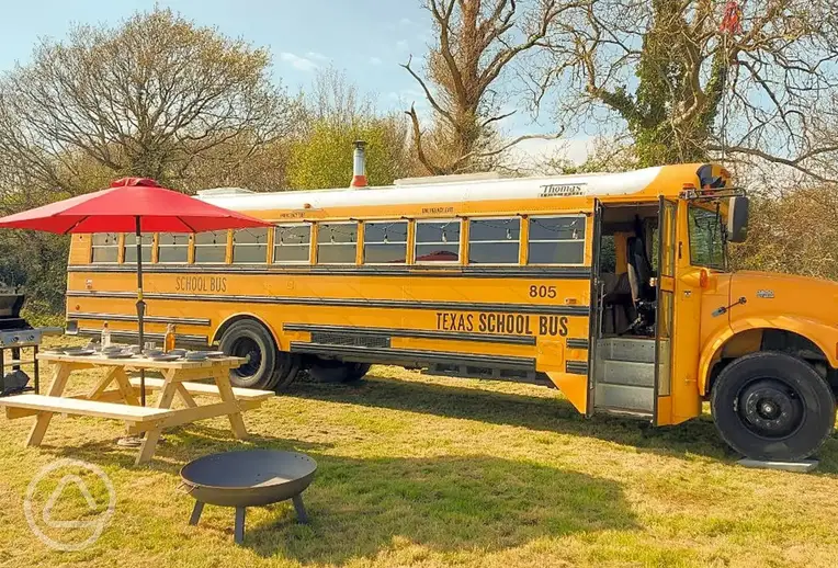 American-inspired glamping school bus with a picnic bench and fire pit
